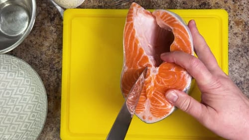 Cutting salmon fish with a knife for further cooking, preparing the fillet and removing the bones.