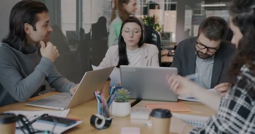 Group of Businesspeople Talking Sitting at Desk During Meeting in Office