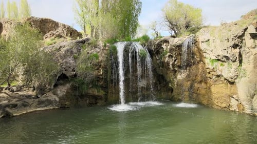 Scenic Waterfall Flowing into Tranquil Green Pool