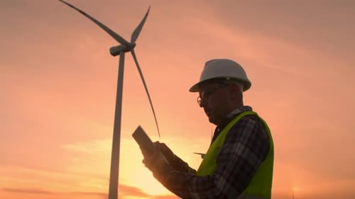 Engineer Protective Helmet at Windmills Checks Operation Turbines Using a Tablet