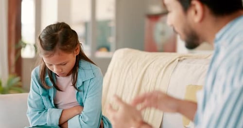 Un père en colère gronde sa petite fille dans le salon de leur maison familiale pour cause de conflit