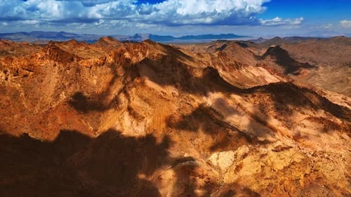 High bare rocks close to the sky. White clouds throwing shadows on the mountains. Top view.