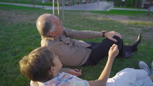 Grandfather and Grandson Chatting on the Grass