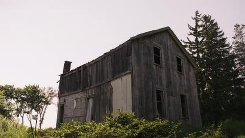Profile backlit view of abandoned wooden cabin broken windows, grey wood