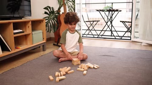 Boy Plays Tower Building Game on Living Room Rug