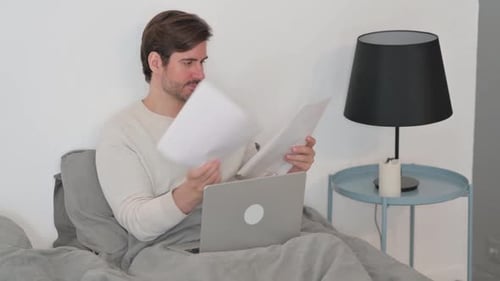 Adult Working on Laptop in Bed at Home