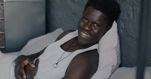 Smiling Man Relaxing in Bed at Home