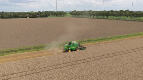 Golden cereal harvest on broad field, combine machine at pace, Netherlands
