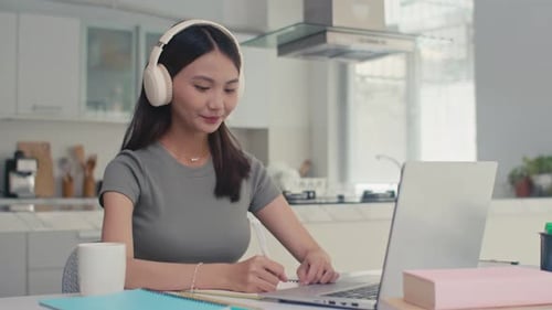 Woman at Desk Working on Laptop and Writing