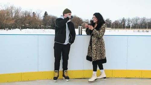 Couple Drinks Coffee on Outdoor Ice Skating Rink