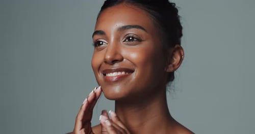 Touch face, skincare and beauty of Indian woman in studio isolated on gray background