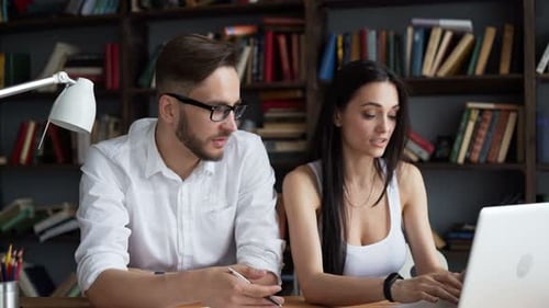 Man and woman working on a laptop indoors