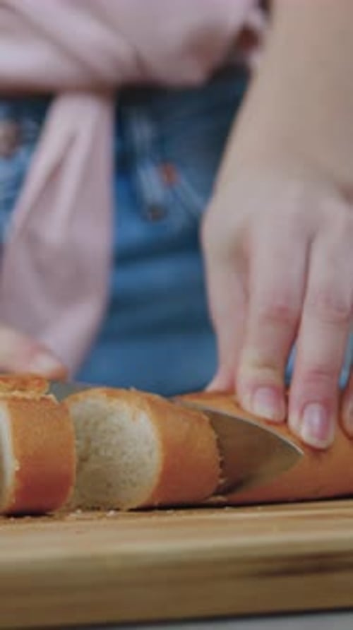 Slicing Fresh Baguette Bread Loaf on Wooden Cutting Board