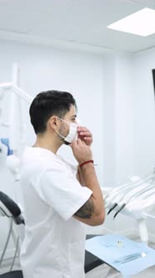 Vertical video of a male dentist putting on a surgical mask in a modern dental clinic