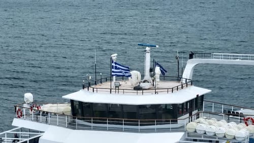 Close Up of Ferry Boat Deck Navigation Radar Spinning and Greek Flag Waving in Wind with Blue Sea