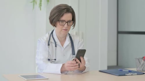 Old Female Doctor Browsing Smartphone in Clinic