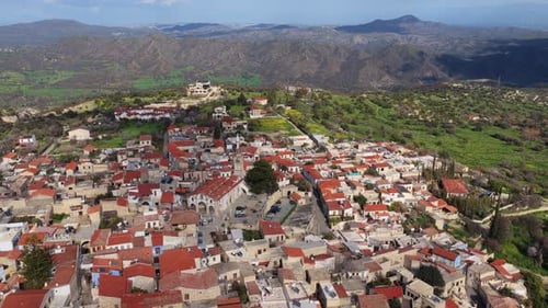 Aerial drone view of a traditional Cypriot village featuring a historic church with bell tower and r