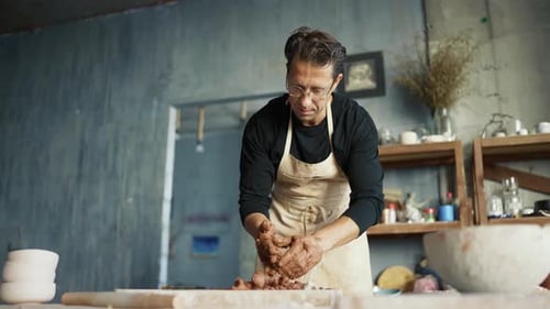 Man Shapes Clay at Pottery Studio Workbench