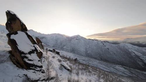 Snowy Mountains and Rock Formation at Sunrise