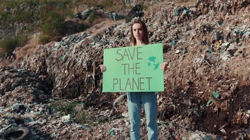 Young Adult Holding Sign at Landfill Site