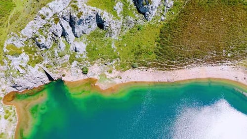 Descend above the deep turquoise lake with clear water reflecting bright sunlight