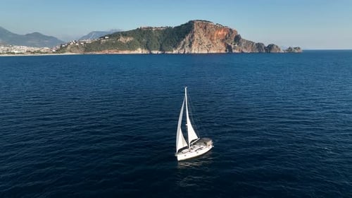 Eine wunderschöne weiße Segelyacht segelt langsam im Wind zum Hafen vor dem Hintergrund von