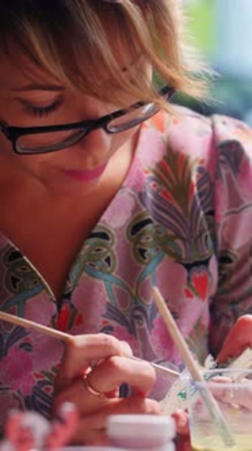 Femme artistique créant des motifs délicats dans une robe colorée pendant la journée dans un studio lumineux