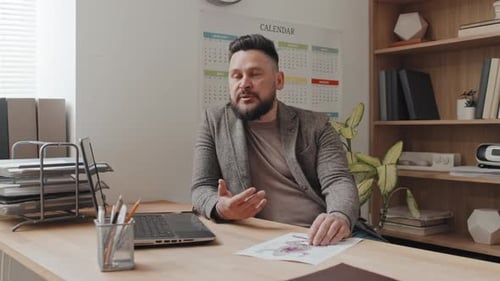 Man Sitting at Desk Talking During Video Call