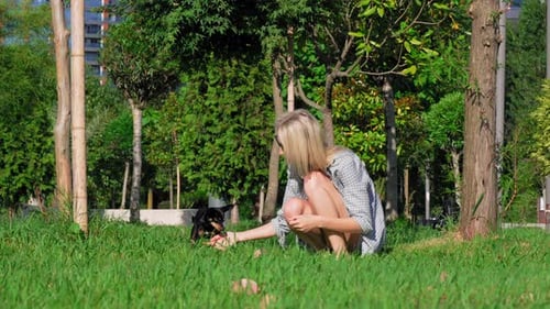 Woman Playing with Dog in Urban Park