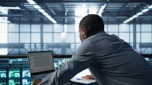 Technician Coding on Laptop in Data Center Managing Server Virtualization