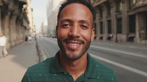 Close-up of happy young man standing on the street. Guy smiles at the camera