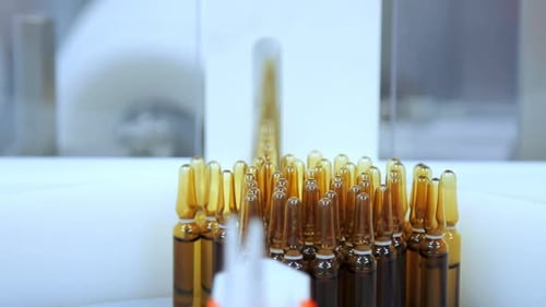 Yellow medical ampoules on automated conveyor line at pharmaceutical factory
