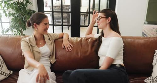 Two women friends chatting on couch at home