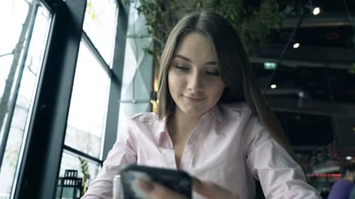 Young, Pretty Woman Using Smartphone Sitting in Cafe 20s