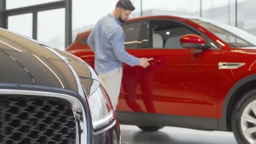 Young Handsome Man Exploring Sleek Cars at a Modern Automobile Dealership