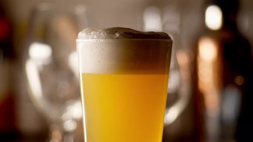 Close up of craft Beer being poured in to a pint glass, light background