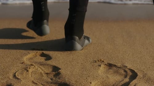 Surfer, der bei Sonnenuntergang zum Strand geht, bereitet sich auf das Surftraining vor und sucht nach Wellen