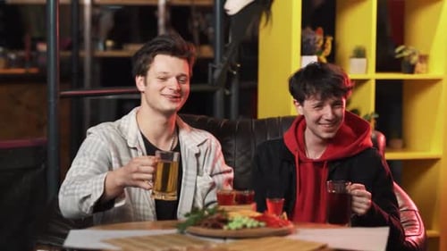 Dos tipos están bebiendo cerveza sentados en una mesa en el bar