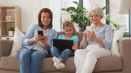 Three Generations of Women Using Technology on Couch