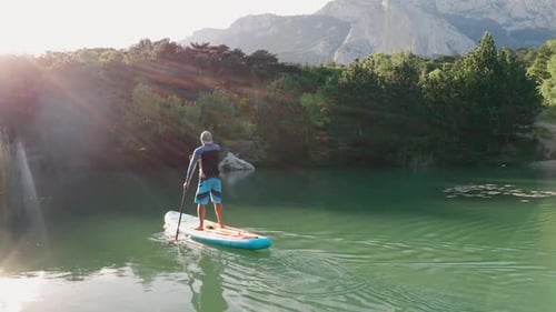 Standup Paddle Boarding Surfer Rows Along Small Lake Water