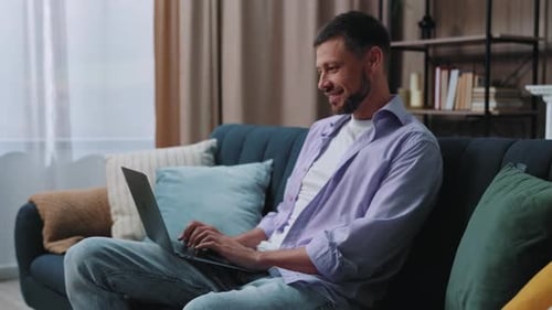Man Typing on Laptop While Sitting on Couch