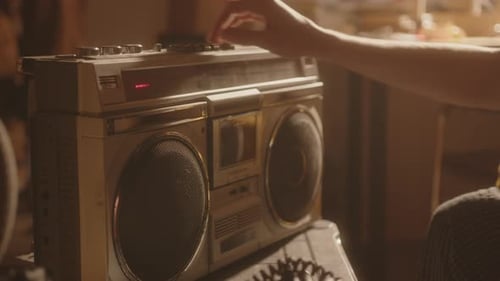 Jeune homme triste allumant de la musique sur une boombox rétro dans une pièce ensoleillée