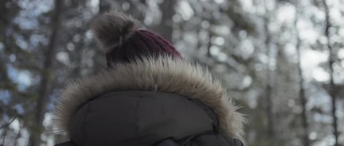 Close up behind view of a woman hiking in the winter forest.