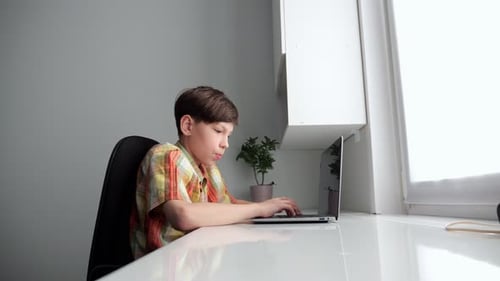 Young Student Typing on Laptop at Home