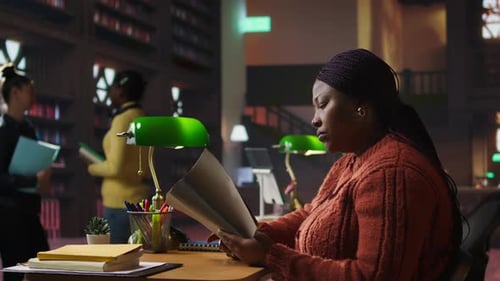 Confident Tutor Reading Notes and Preparing Teaching Materials at a Library Desk