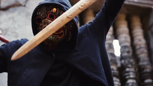 Person in Mask Holds Carved Sword
