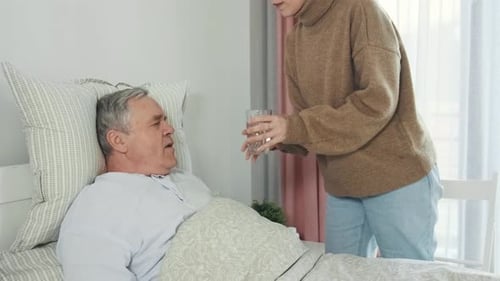 Woman Gives Man Pill and Water in Bed