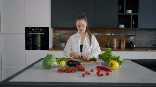 Woman Cuts Vegetables Smiling in Modern Kitchen