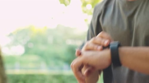 Young Handsome Man using Smart Watch during Morning Run in Park