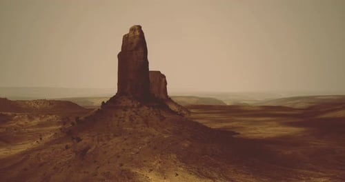 Massive Rock Formation Stands Tall Against a Vast Desert Landscape in Daylight